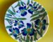 A wide wheel thrown porcelain bowl with a botanical design of blue irises on the surface.